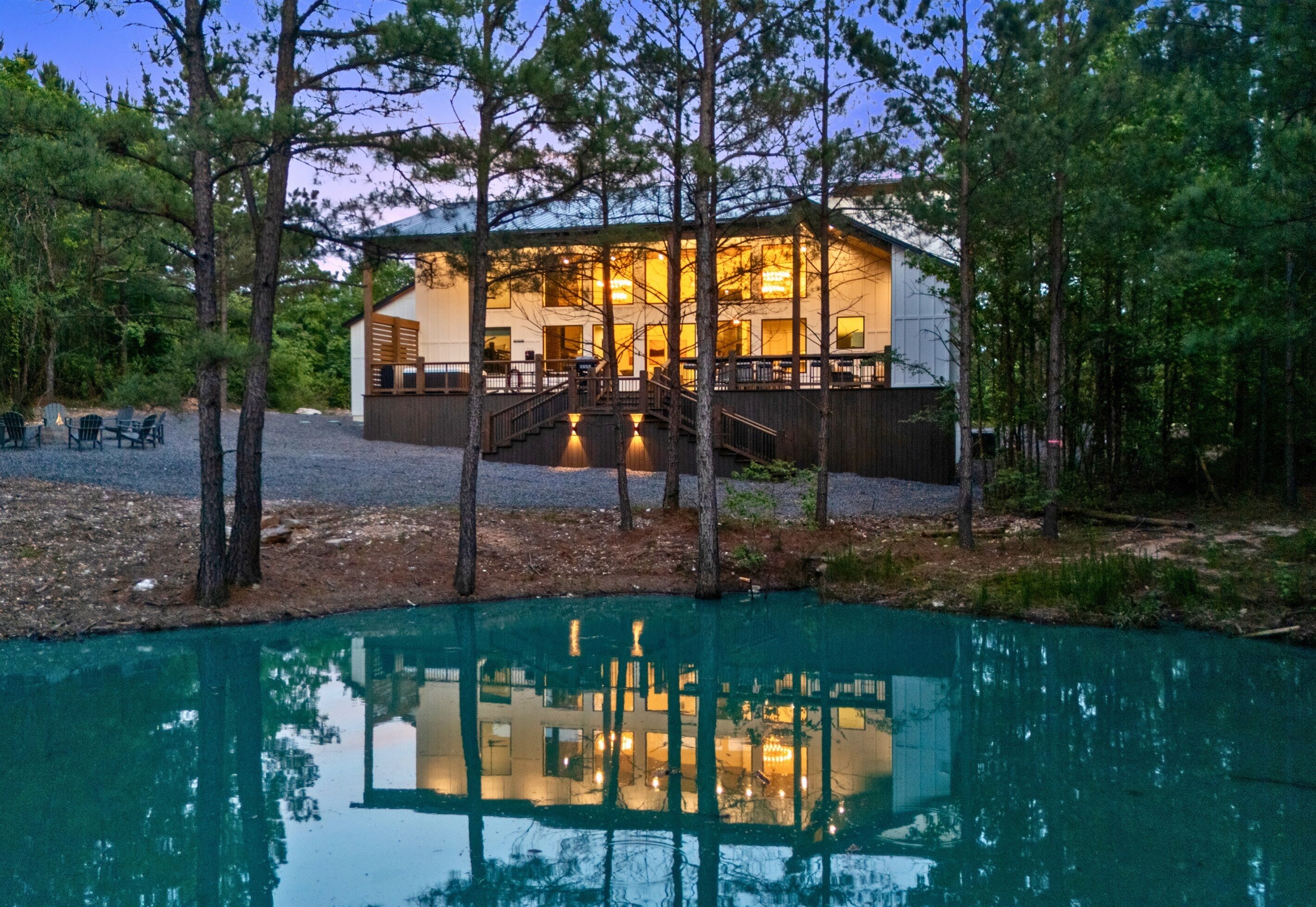 A lodge with a pool, surrounded by trees, and a staircase leading to the entrance.