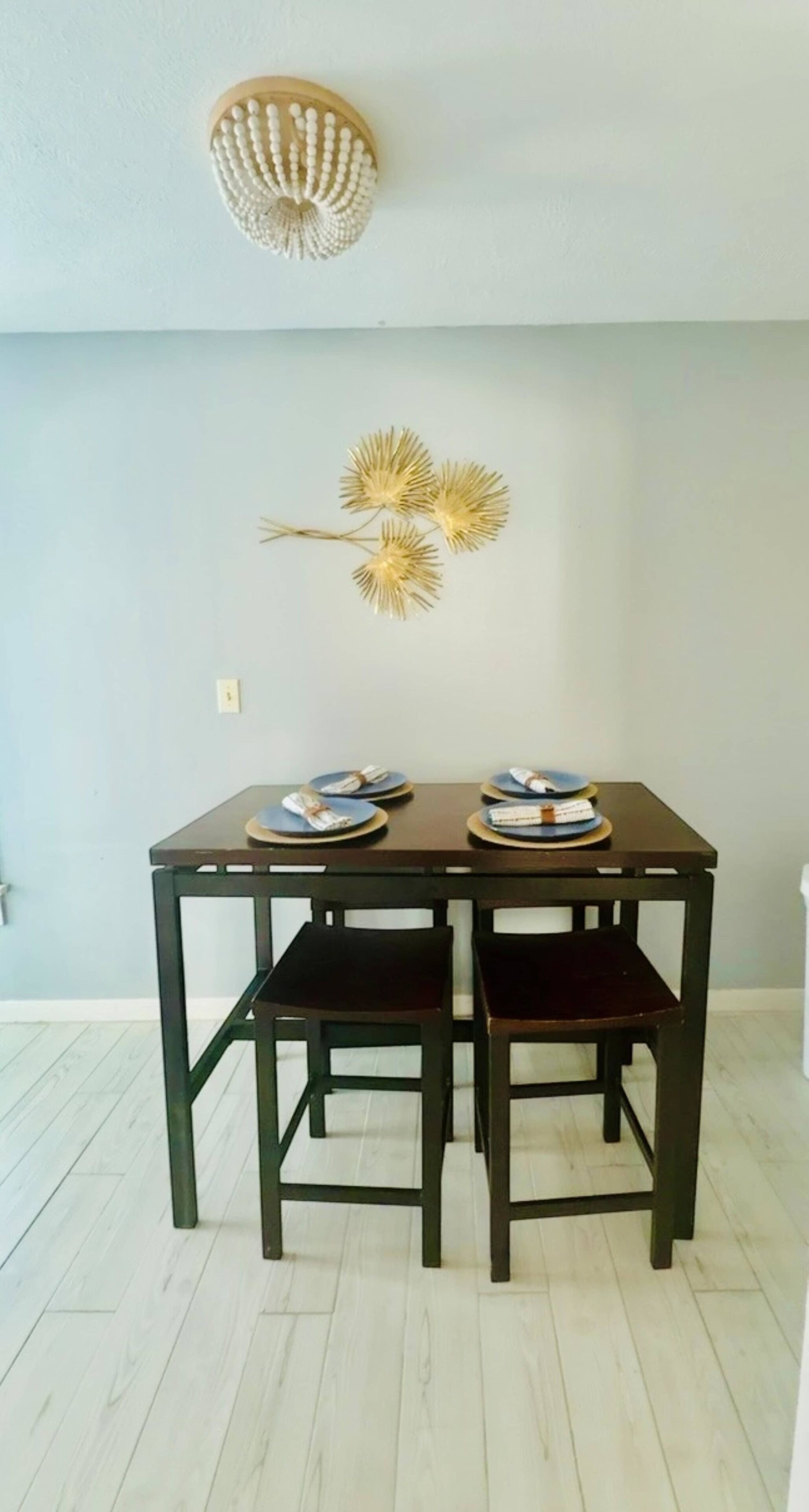 A dining area with a dark wooden table and matching chairs, two plates with food, and a wall-mounted decorative light fixture.