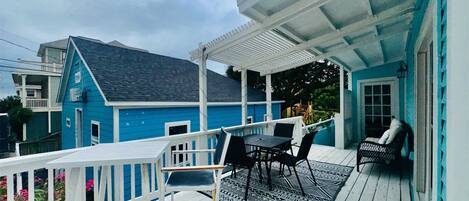 A blue house with a porch, a table with chairs, and a covered area.