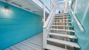 Un escalier menant à une terrasse avec un mur bleu et une balustrade blanche.