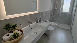 Ein modernes Badezimmer mit großem Spiegel, zwei Waschbecken, Toilette und einer Duschkabine.