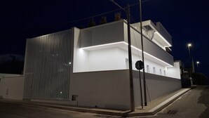 Ein modernes Gebäude mit flachem Dach, großen Fenstern und einer sichtbaren Treppe.
