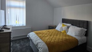 A bedroom with a bed, a nightstand, a dresser, and a window with blinds. - Room-cozy Guest Rooms in Bedford With Sh (Bedford)