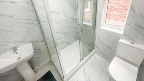 A bathroom with a glass-enclosed shower, a sink, and a toilet. - Room-cozy Guest Rooms in Bedford With Sh (Bedford)