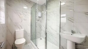 A modern bathroom with a glass-enclosed shower, a toilet, and a pedestal sink. - Room-cozy Guest Rooms in Bedford With Sh (Bedford)