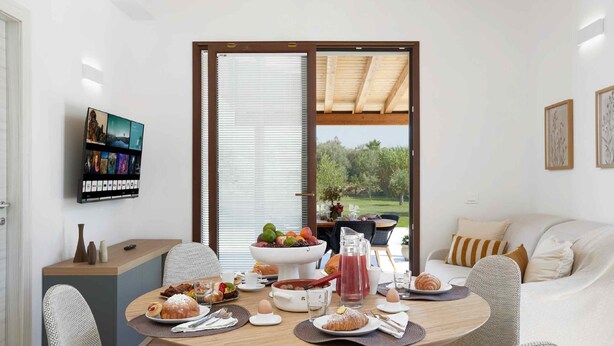 Een eetgedeelte met een ontbijt gedekte tafel, een schaal fruit en een koffiehoek.