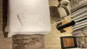 A modern hotel room with a bed, a wooden side table, a mirror, and a seating area. - Miltilon (Xylokastro-Evrostina)