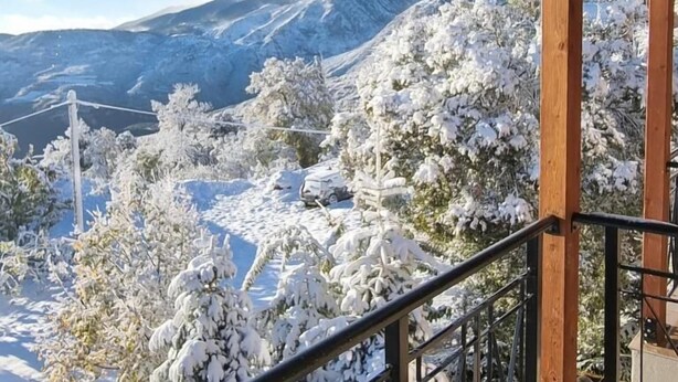 A wooden balcony with a metal railing overlooking a snowy mountain landscape. - Miltilon (Xylokastro-Evrostina)