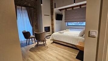 A bedroom with a bed, a chair, a television, and a window.