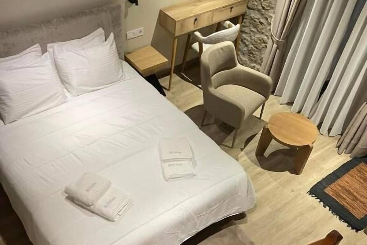 Habitación de hotel con cama, escritorio, silla, una mesita redonda y espejo.
