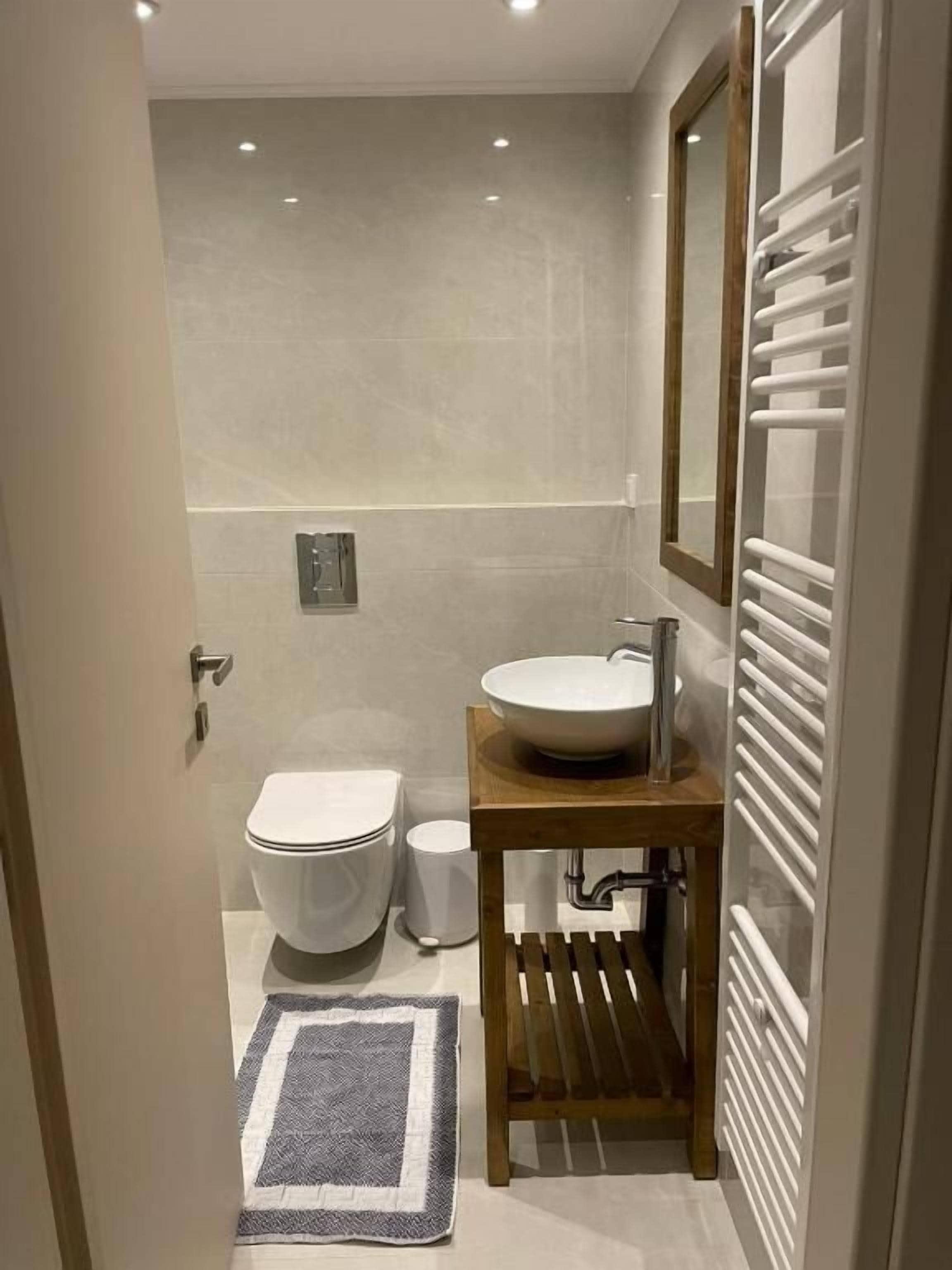 A bathroom with a toilet, sink, mirror, and towel rack.