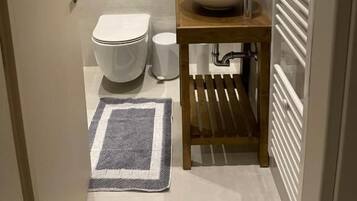 A bathroom with a toilet, sink, mirror, and towel rack.