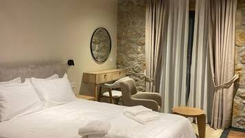 Een slaapkamer met een groot bed, een bureau, een stoel en een stenen muur.