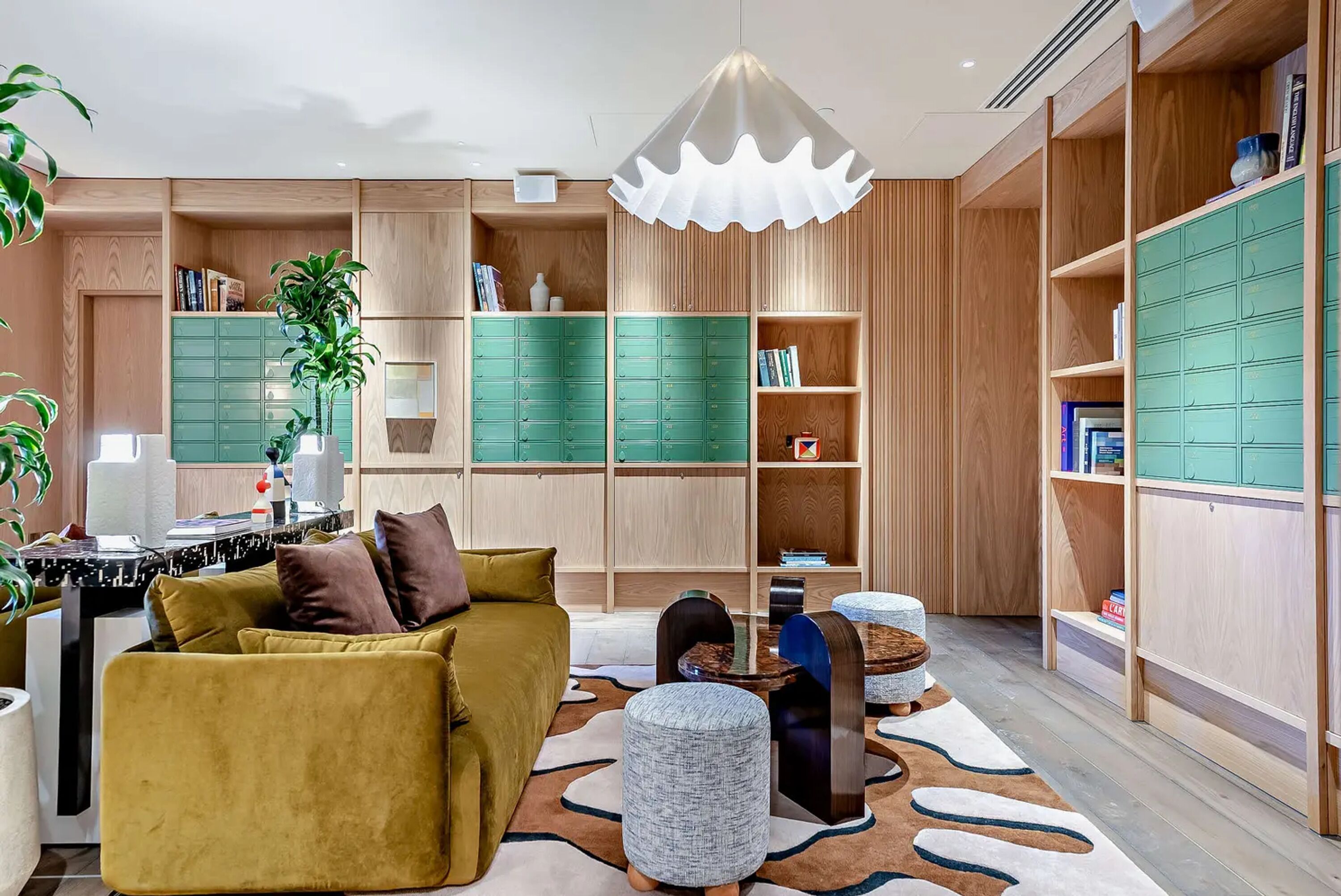 A modern living room with a sofa, ottomans, a coffee table, and built-in wooden shelving.