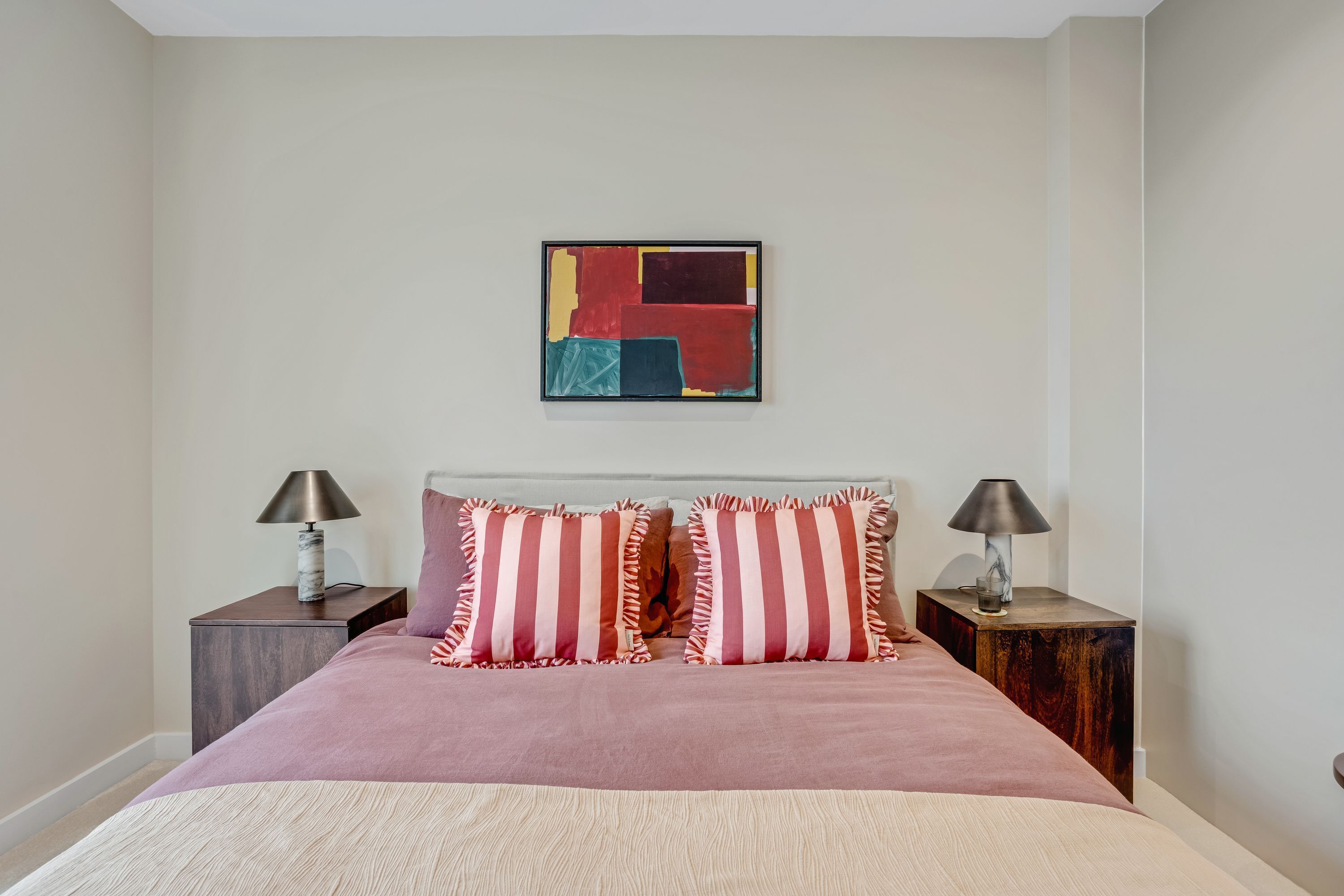 A bedroom with a bed, two nightstands, and a wall art piece.