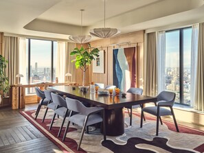 A modern dining area with a large table, six chairs, a potted plant, and a city view through large windows. - Stylish Two-bedroom Flat With a Large Balcony (London)