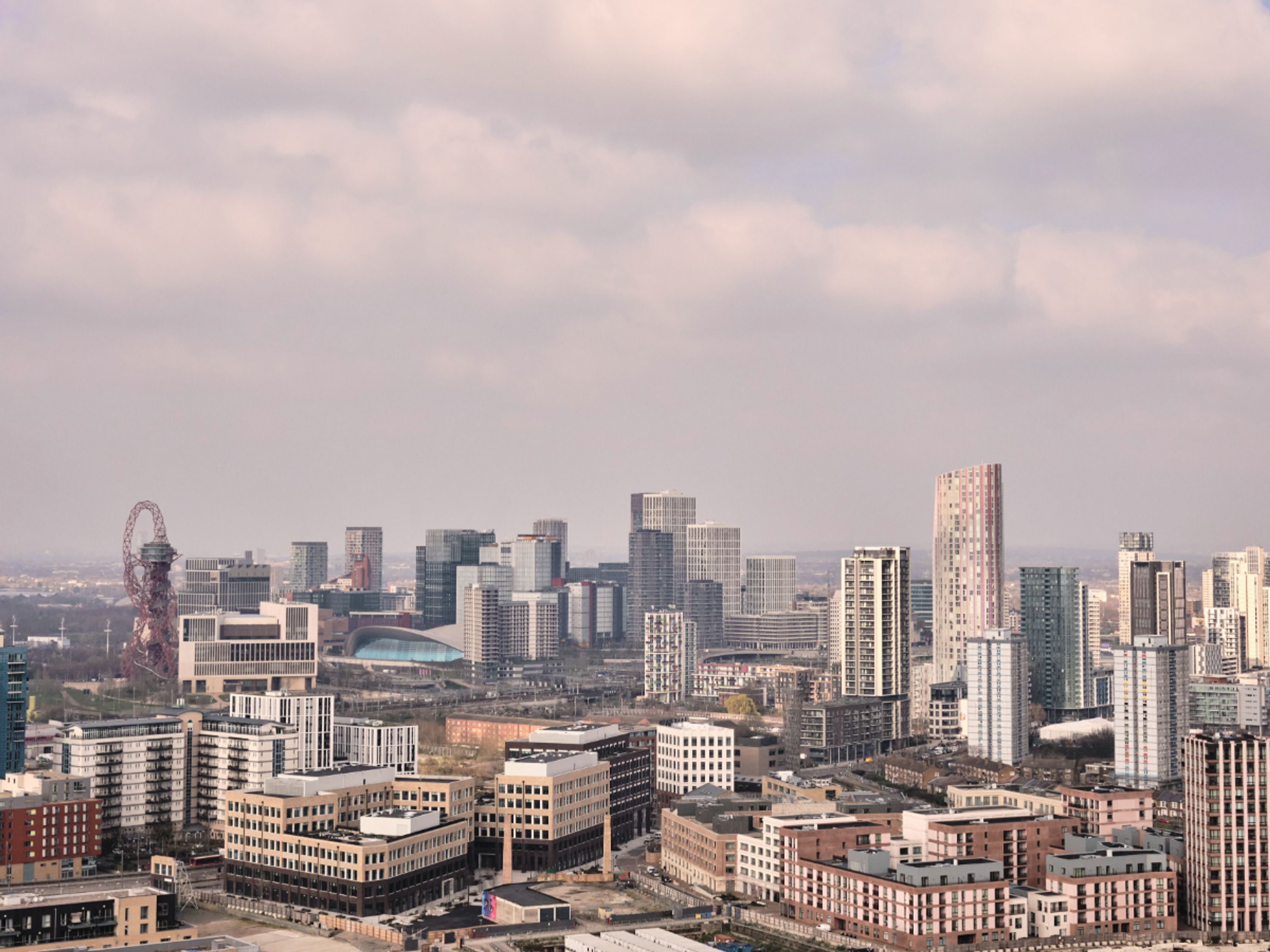 Eine Stadtansicht mit modernen Hochhäusern, einem markanten Riesenrad und einem großen Stadion.