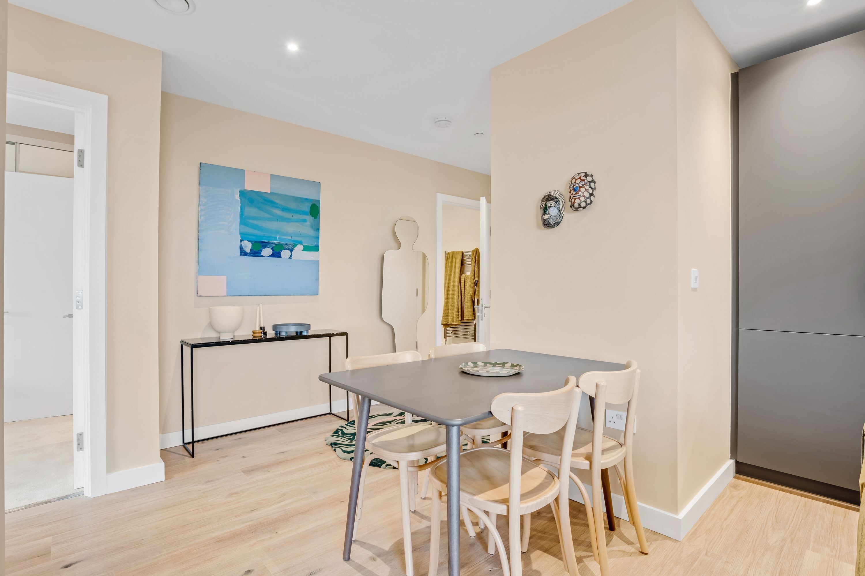 A modern kitchen with a dining area, featuring a table with chairs, a black countertop, and a painting on the wall.
