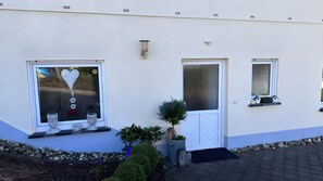 Un edificio con fachada blanca, una puerta y ventanas decoradas con corazones.