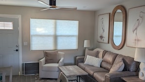 Una sala de estar con sofá, sillón, mesa de centro y mesa de comedor.