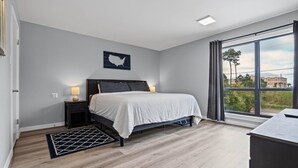 Un dormitorio con cama, mesitas de noche, una alfombra, una ventana con cortinas y un mapa colgado en la pared.