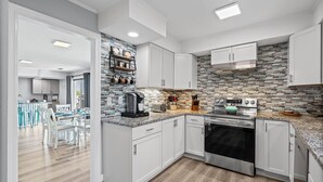 Una cocina moderna con armarios blancos, salpicadero de azulejos y horno empotrado.