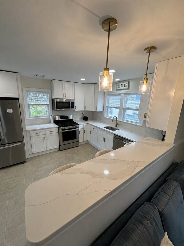A modern kitchen with white cabinets, stainless steel appliances, and a marble island.