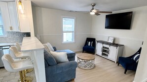 A modern living room with a sofa, a coffee table, and a TV mounted on the wall. - Cozy Wildwood House, Great Location, Private Parking, Walking distance to beach (Wildwood)