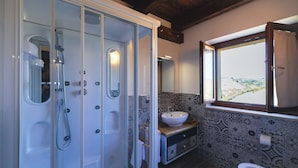 Casa de banho com chuveiro em cabine de vidro, lavatório e sanita.