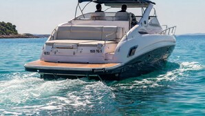 A motorboat with a cabin and seating area, moving through clear blue water. - Dream boat (Tunis)