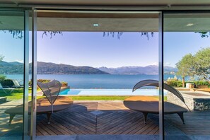 Ein moderner Sitzbereich im Freien mit Blick auf einen See und Berge.