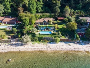 Ein geräumiges Haus mit Schwimmbad, umgeben von üppiger Vegetation und einem Strand.