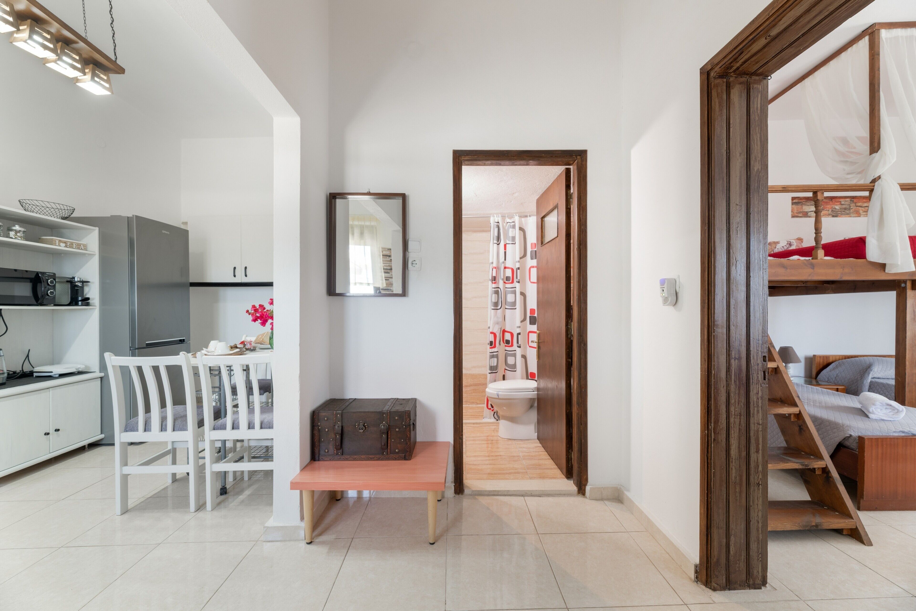 A modern, compact living space with a kitchenette, a dining area, a bathroom, and a bed.