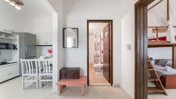 A modern, compact living space with a kitchenette, a dining area, a bathroom, and a bed.