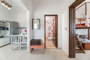 Een moderne, compacte leefruimte met een kitchenette, een eethoek, een badkamer en een bed.