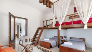A room with a bunk bed, a single bed, a glass-top table, a wooden chair, and a staircase. - Casa Di Rena Country House: Panoramic Castle View & Endless Blue (Kritinia)