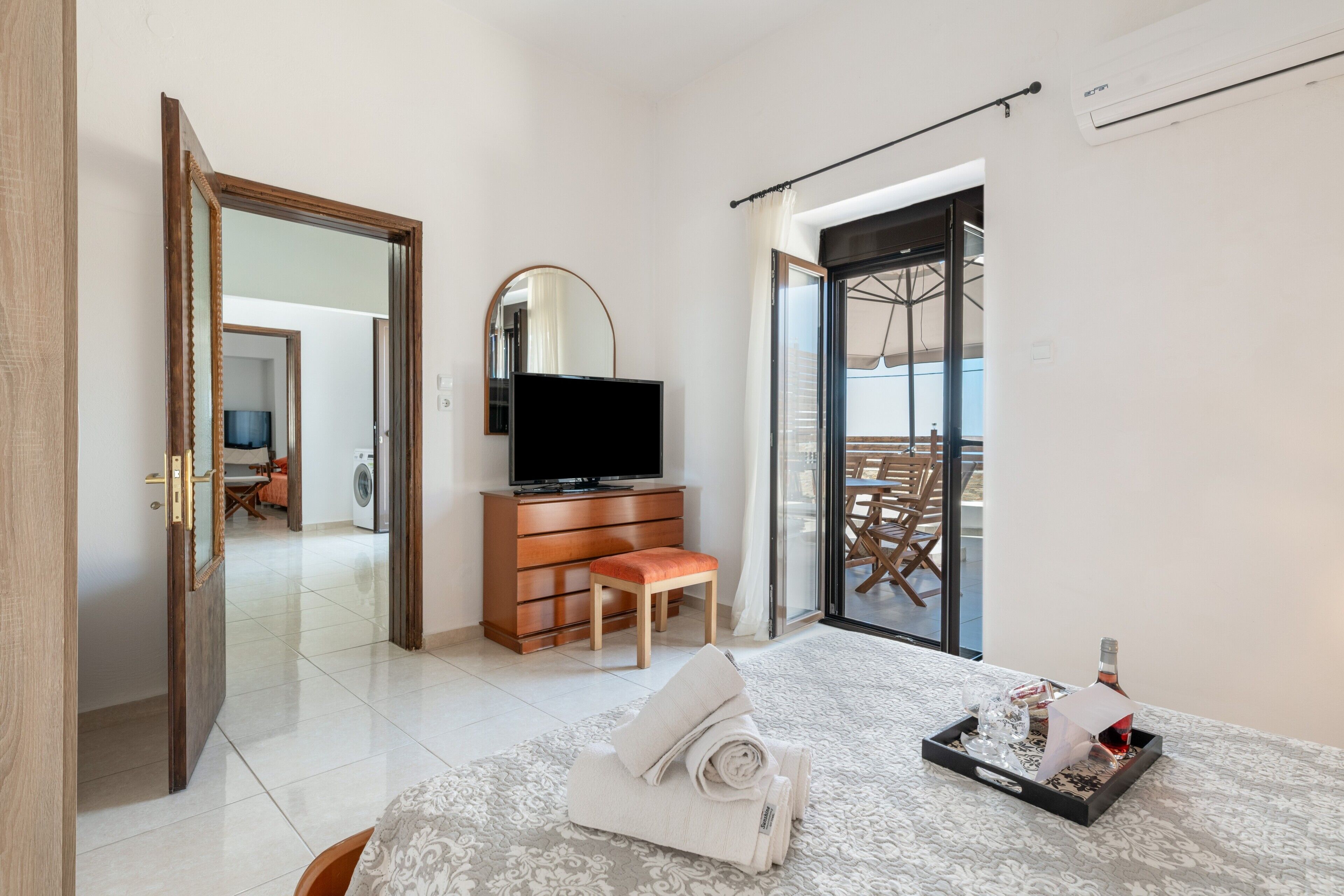 Une chambre d’hôtel comprenant un lit, une télévision, une commode, une chaise, un balcon avec une table et une vue sur l’extérieur.