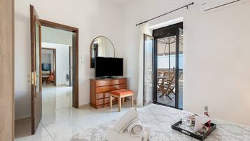 Une chambre d’hôtel comprenant un lit, une télévision, une commode, une chaise, un balcon avec une table et une vue sur l’extérieur.