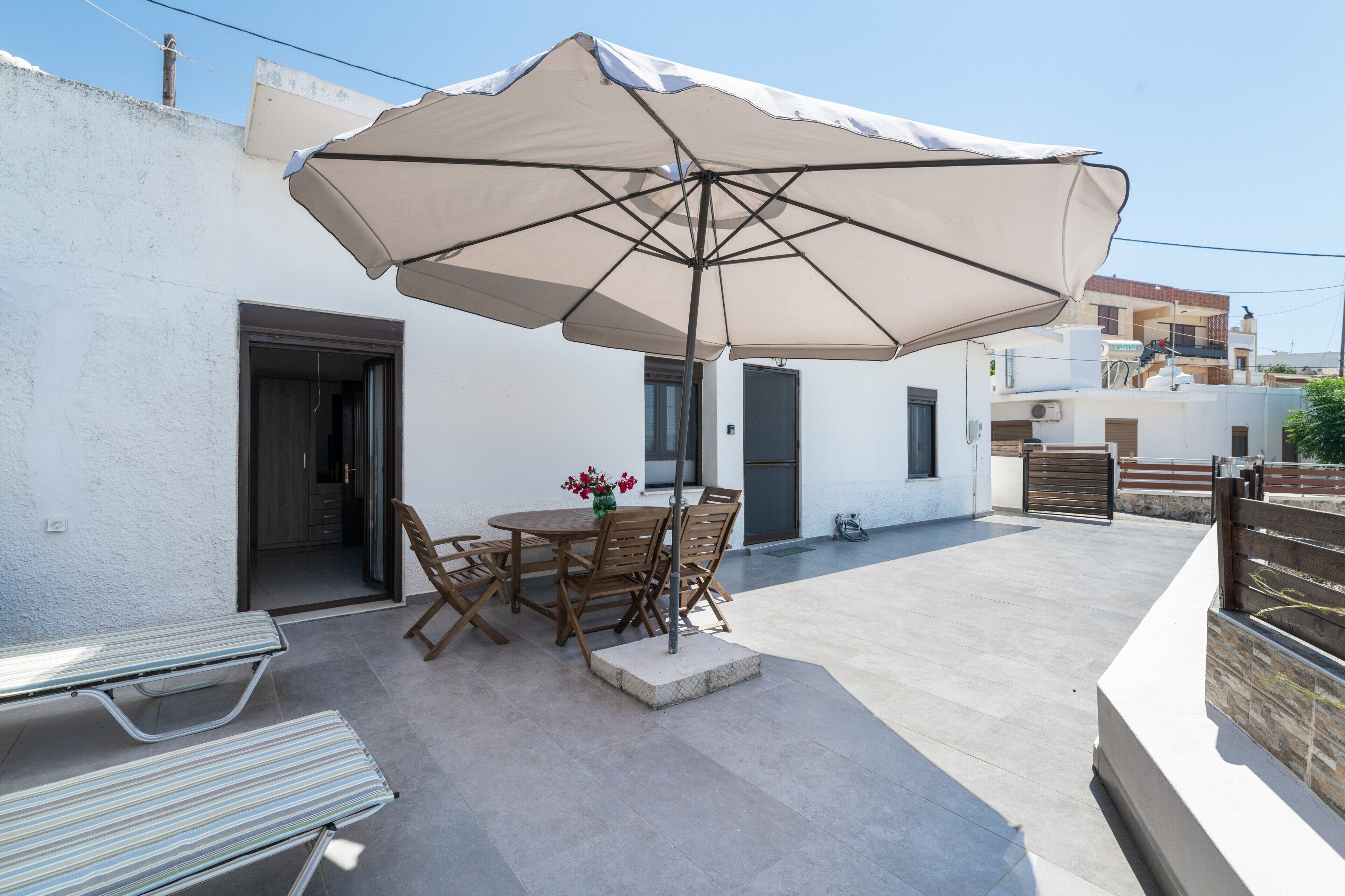Une terrasse extérieure avec une table, des chaises et un grand parasol.