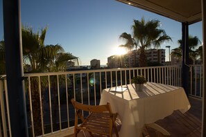 A balcony with a table and chairs, overlooking a cityscape with palm trees and buildings. - Lentiscares 212 by At Home Costa del Sol (Torrox)
