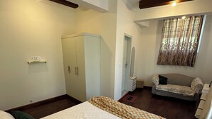 A bedroom with a bed, a wardrobe, a vanity, a sofa, and a ceiling fan.