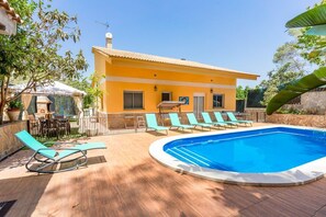 Ein Poolbereich mit Pool, Liegestühlen und einem Gebäude mit einem Ziegeldach.