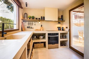 Una cocina moderna con un ventanal grande, estanterías empotradas y una zona de comedor con mesa de madera.
