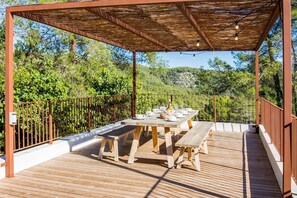 An outdoor wooden deck with a table set for dining, surrounded by a metal fence and a pergola with string lights. - Villa Falco - Four Bedroom Villa, Sleeps 10 (Vora-sitges)