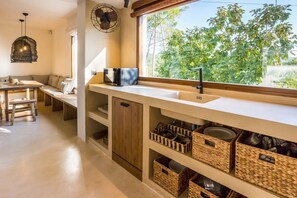 Una cocina con un ventanal amplio, armarios de madera y cestas tejidas.