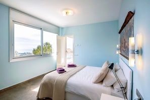 Ein Schlafzimmer mit einem Bett, einem Fenster, einer Tür und einer Wandleuchte.