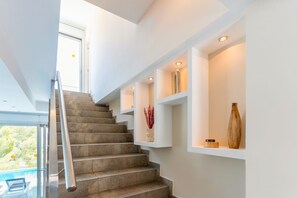 A modern staircase with built-in shelving, a glass railing, and a view of the outdoors. - Villa Giovanna I - Five Bedroom Villa, Sleeps 12 (Sitges)