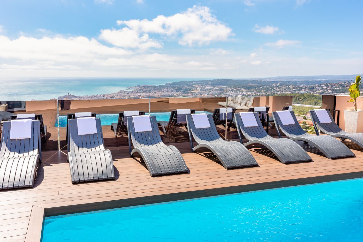 Piscina en la azotea con sillas de descanso y vista panorámica de la ciudad.