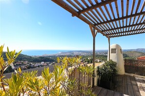 Eine Holzpergola mit Blick auf eine Küstenstadt und Hügel.