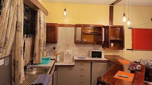 Une cuisine de taille réduite, équipée d’un évier, d’un four à micro-ondes et de meubles de rangement en bois.
